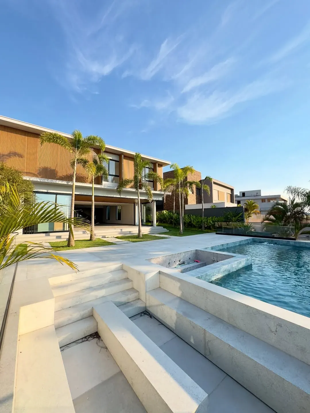 Área externa de residência com piscina, deck e fachada em madeira