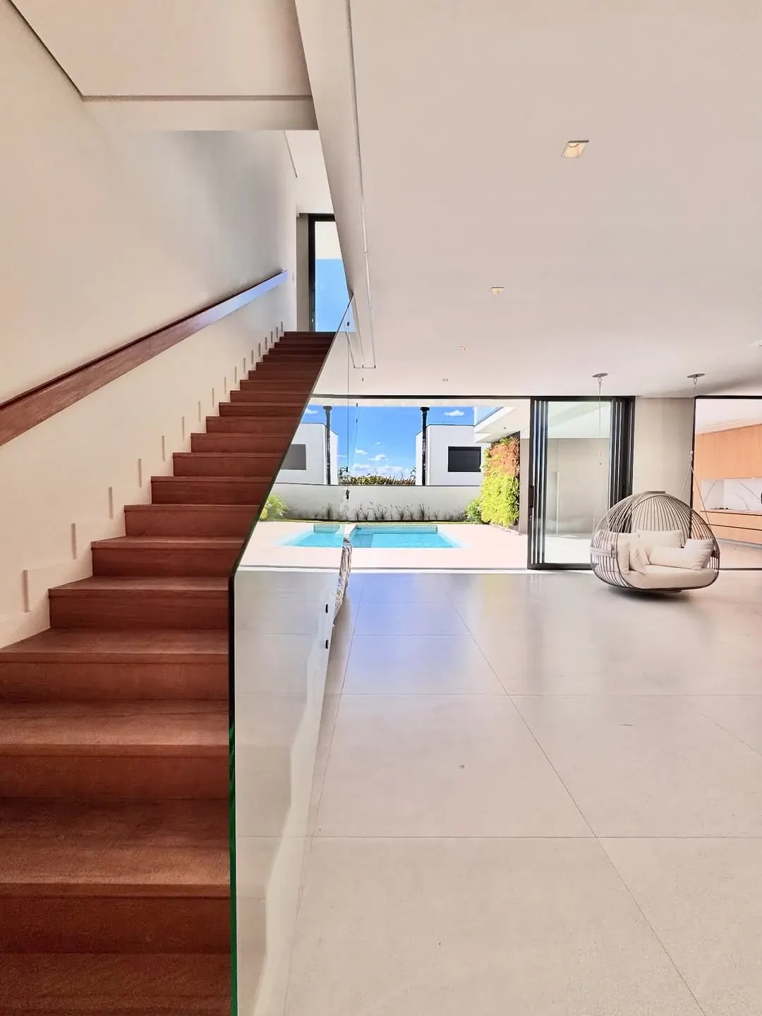 Interior integrado com escada em madeira, sala e vista para área externa