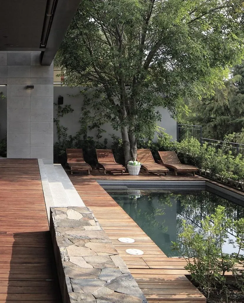 Piscina com deck em madeira e paisagismo em residência contemporânea